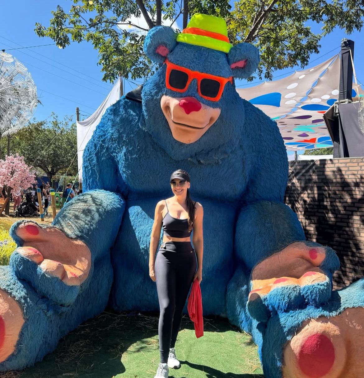 Mulher posando com mascote gigante em evento ao ar livre