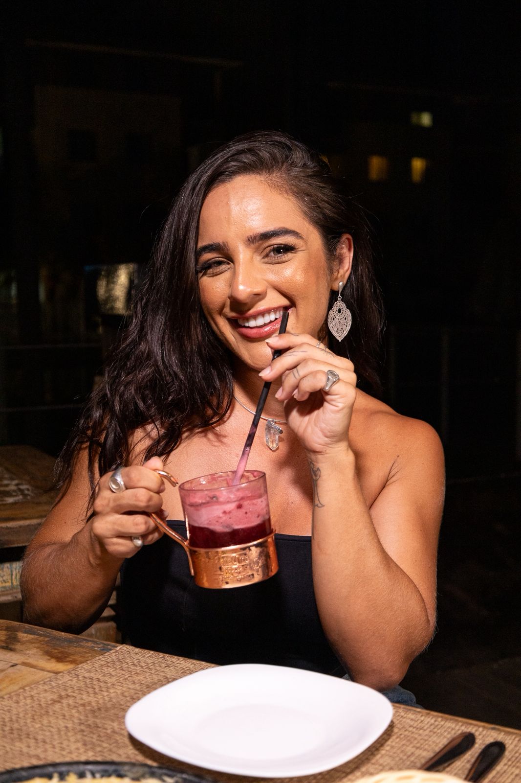 Mulher saboreando cocktail com canudo